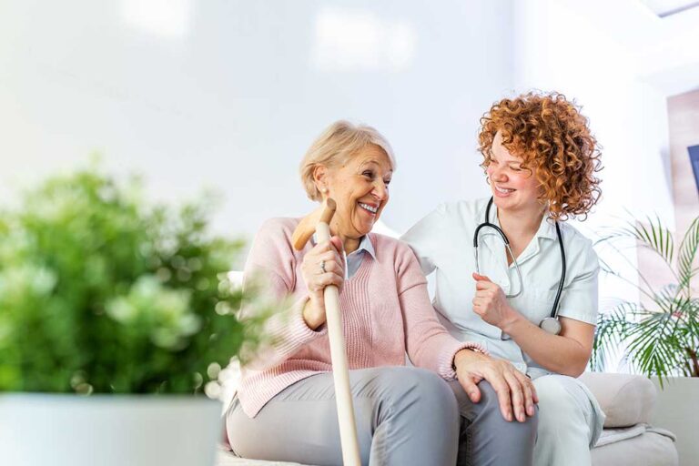 Two seniors and a staff member walking together in a bright, welcoming common area with comfortable seating.