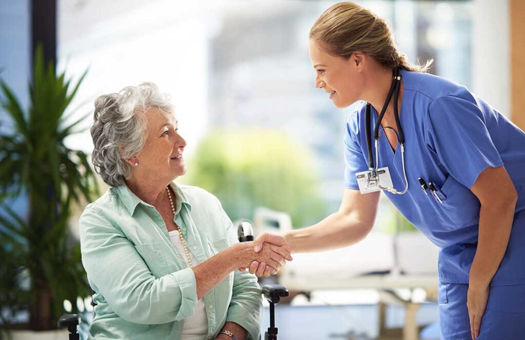 Older adult choosing clothing while a caregiver offers support in a bright assisted living room.