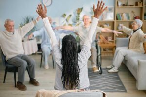 Older adult arranging photographs and personal belongings in a bright assisted living apartment with family support.