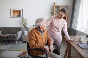 Older adult and family member sort labeled boxes beside a comfortable chair in a bright room.
